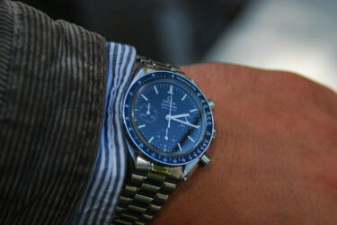 Man wearing watch on left hand, wearing striped shirt