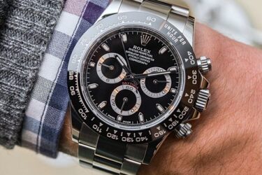 man wearing Rolex Cosmograph Daytona Watch Black on wrist with checked shirt